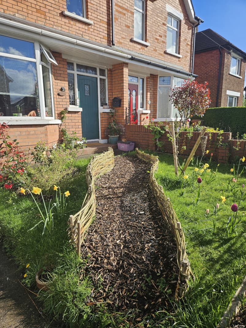 Woven willow border running along a path in a front garden